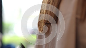 Close-up side view female hands holding hair with comb cutting endings with hair clipper in slow motion. Closeup