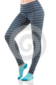 Close up side view of fit woman legs warming up in colorful striped sports leggings wearing blue socks