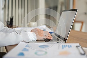 Close-up side view image of a businesswoman working on her laptop, responding to emails at her desk