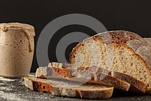 Close up side view image of a freshly baked thick crust sourdough artisan bread with an active rising sourdough starter culture in