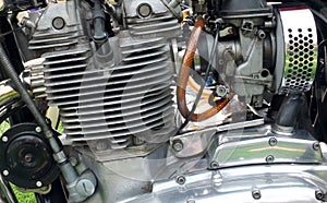 Close up side view of a large vintage motorcycle engine with cylinders connecting leads and chrome steel parts