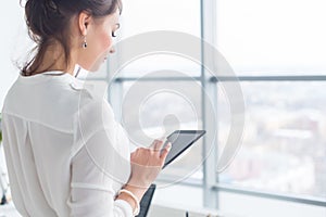 Close-up side view portrait of an employee texting, sending and reading messages during her break at the workplace.