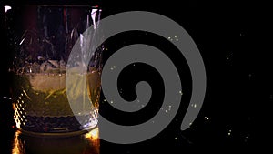 Close-up. Side VIew of Pouring Glass of Whiskey. Pouring of scotch whiskey or cognac into glasses with ice cubes on dark