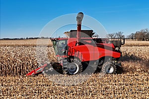close up side view of a red harvester combining corn
