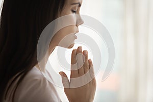 Superstitious young woman believer pray to God at home photo