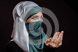 Close up side view shot of Muslim young woman in green hijab is praying the God