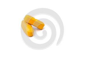 Close up side view of two orange pills which are isolated over the white background.