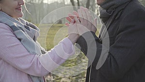 Close-up side view of unrecognizable young Caucasian man breathing at woman`s hand. Happy smiling couple spending free
