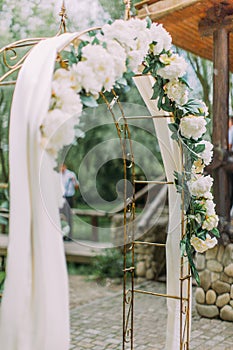 Close-up side view of the wedding arch with white flowers.