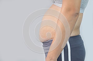 Close-up side view of woman excessive belly fat  on gray background. Woman fat belly. Obesity and Overweight Concept