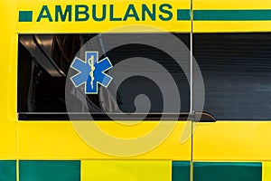 Close up side view of a yellow and green Swedish ambulance vehicle.