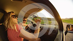 CLOSE UP: Side view of a young couple dancing in their car while they drive.