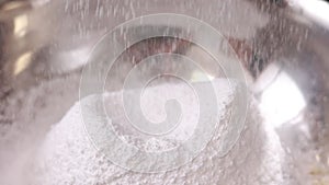 close up of sifting white flour or sugar powdered with sieve in steel bowl for pie, french dessert macarons or macaroons