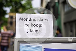 Close-up of a sign poster announcing in Dutch that medical face masks against the coronavirus are available at a local shop