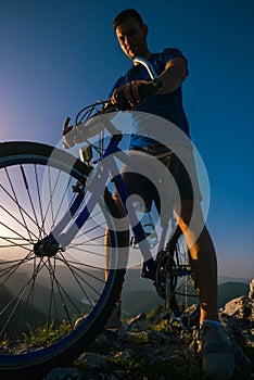 Close up silhouette of an athlete mountain biker riding his bike on rocky mountains