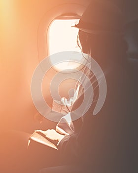 Close up silhouette of caucasian woman passenger look to window sit on chair on flying commercial airplane. Passenger on the plane