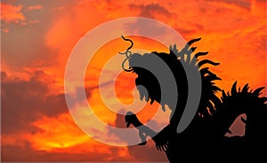 Close-up silhouette dragon statue from roof top of Chinese Temple on sunset sky background with copy space