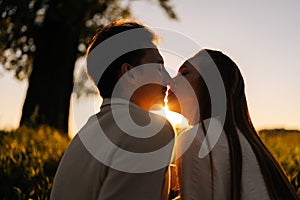 Close-up silhouette view of beautiful young couple in love sitting hugging and kissing enjoying their time together