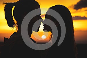 Close-up of the silhouettes of a young millenial couple in love getting ready to kiss with a man and girl against the