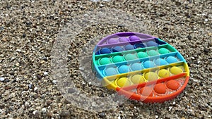 Close-up of silicone antistress, pop it fidgets in sand outdoors