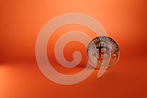 Close up of a silver Bitcoin coin isolated on an orange background - the concept of cryptocurrency