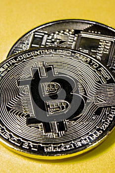 Close-up of silver Bitcoin coins on yellow background