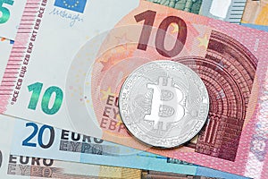 Close up of silver Bitcoin on euro currency background. Macro ph
