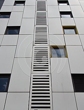 close up of silver colored metal cladding panels on a modern building with repeating windows and geometric grid design