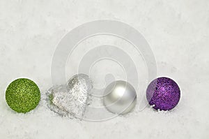 Silver, green and purple Christmas tree decorations on Snow background