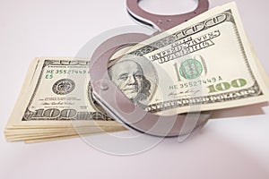 Close up of silver handcuffs and us dollars on white