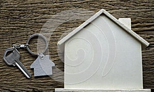 Close-up of Silver key house with house shaped keychain and home mock-up on vintage wooden table background.