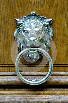 Close up of a silver lion head door knock  on a wooden heavy door