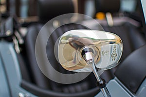 Close up of a silver rearview mirror of a classic car, with the reflection of the photographer