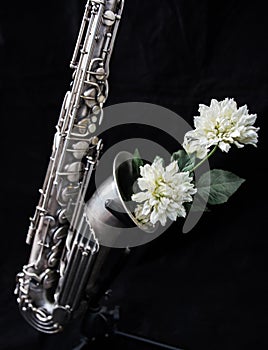 Close up of a silver saxophone decorated with white flowers