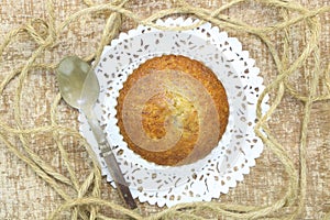 Close up single banana cup cake bakery top view on white doily paper with vintage olded spoon and sack rope
