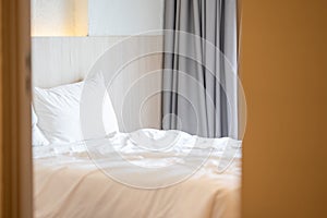 Close up single beds with white bedding are in the cream bedroom of hotel that turn on the headboard light and open the gray