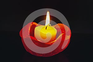 Close up of single burning candle light on black background