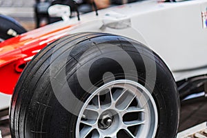 Close-up of a single Formula 1 race car wheel on display, featuring multi-spoke design with screws and nuts, partially visible