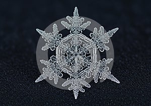 A close-up of a single, intricate snowflake with a hexagonal core,
