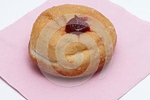 Close up single jam donut on pink napkin
