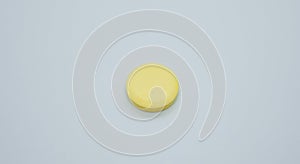 Close-up of single yellow color pill of vitamin C, isolated on the white background.