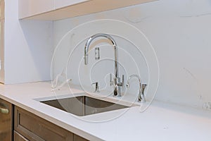 Close up of sinks in modern white kitchen with white stone