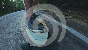 Close-up skateboarder boy riding outdoor. A young man rides a longboard on the highway. Misty road in the forest