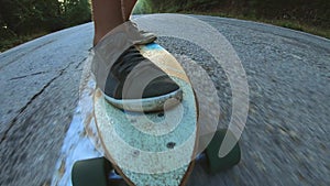 Close-up skateboarder boy riding outdoor. A young man rides a longboard on the highway. Misty road in the forest