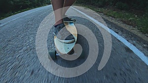 Close-up skateboarder boy riding outdoor. A young man rides a longboard on the highway. Misty road in the forest