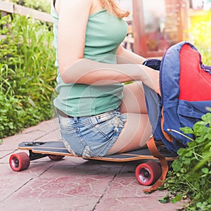 Close-up of skateboarder girl sitting on skateboard outdoor