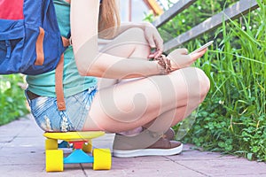 Close-up of skateboarder girl sitting on skateboard outdoor