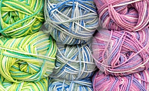 Close-up of skeins of motley threads mixed pastel colors of white, blue, yellow, green ang pink. Threads background