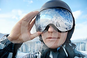 Close Up Of The Ski Goggles Of A Man With The Reflection Of Snowed Mountains. Man On The Background Blue Sky.