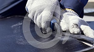 Close up for skilful worker hands cutting black rubber materal. Clip. Man wearing protctive suit and gloves cutting a